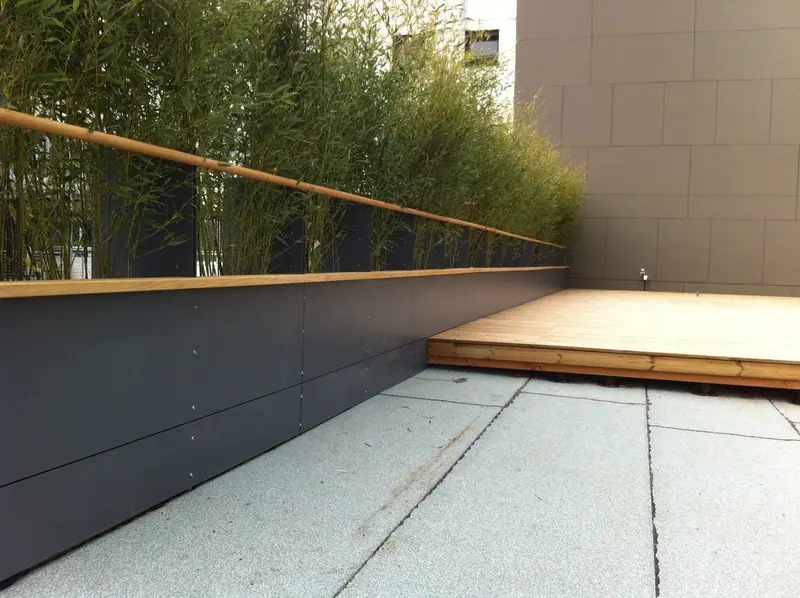 Terrassenbelag mit Holzdielen und Metallbrüstung vor Bambuspflanzen