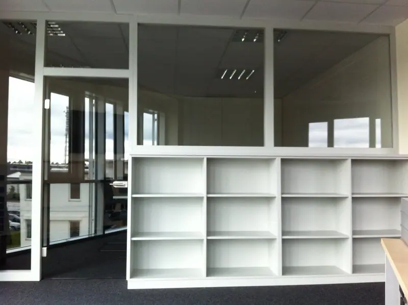 Weißer Raumteiler mit offenem Regal und Glasflächen in einem Büro